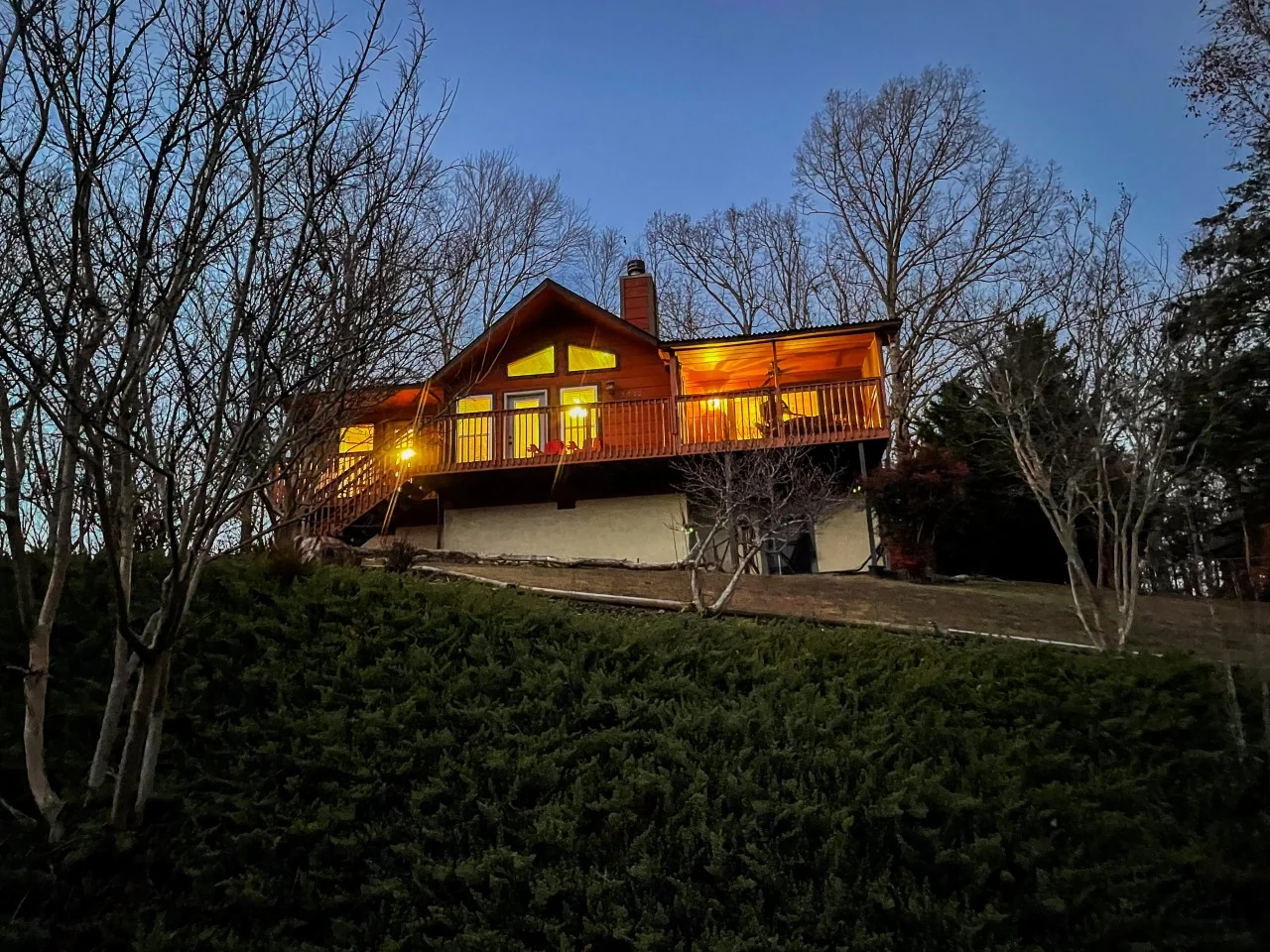 Elevated mountain cabin glowing at dusk surrounded by woods in Pigeon Forge where to stay
