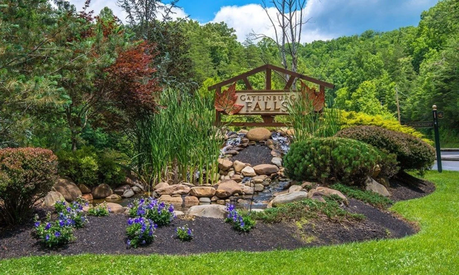 Scenic entrance sign at top rated Airbnb Gatlinburg with stone landscaping and purple flowers