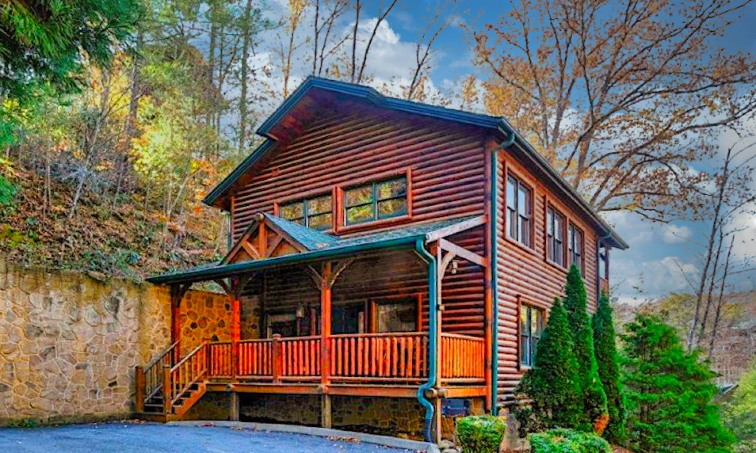 Dog friendly cabin Gatlinburg with rustic log exterior, wraparound porch, and autumn forest setting
