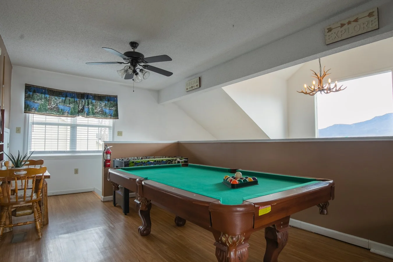 Gatlinburg cabin game room with pool table, antler chandelier, and mountain views through windows