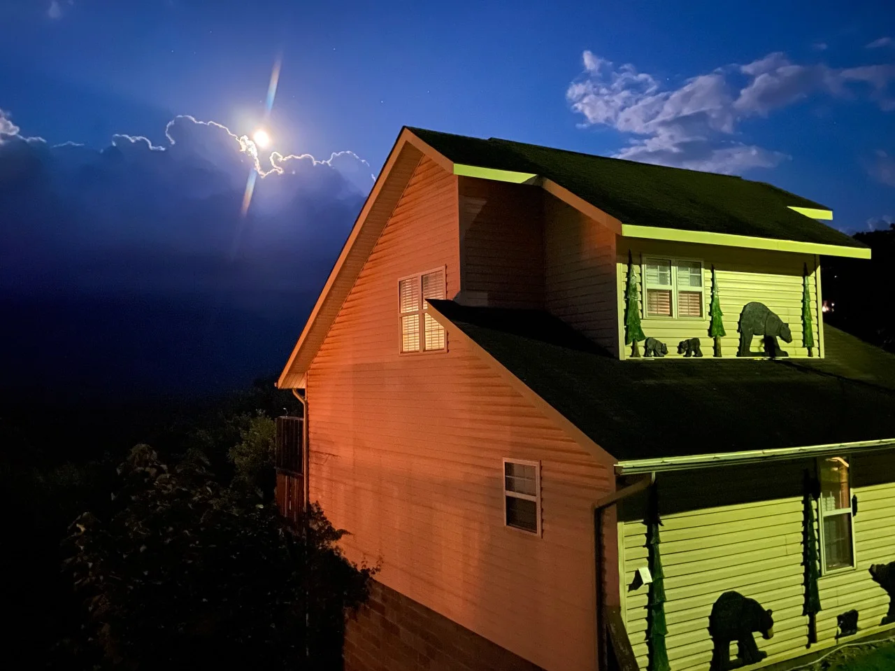 Modern A-frame cabin exterior with warm lighting and mountain views at dusk in Gatlinburg