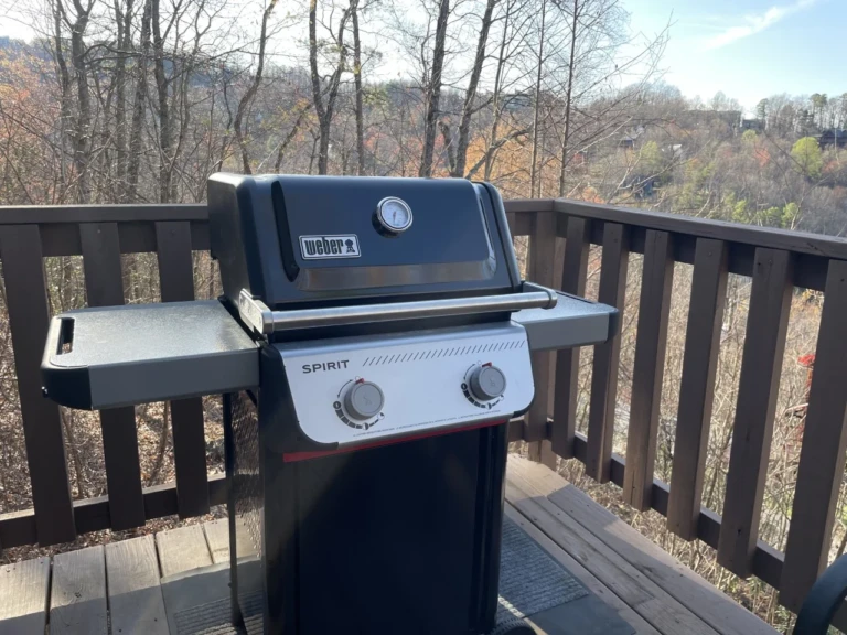 Weber Spirit gas grill on a wooden deck railing overlooking mountain views with fall foliage at Bear Cub Chalet Gatlinburg,
