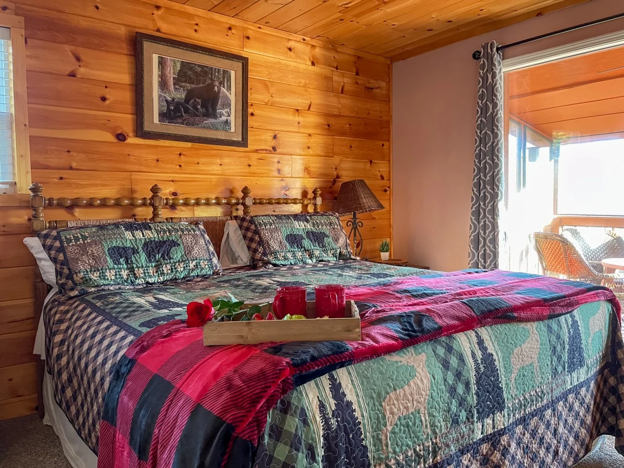 Rustic log cabin bedroom with knotty pine walls, red and teal quilted bedding, and wildlife art at Serenity View, Bear Crest