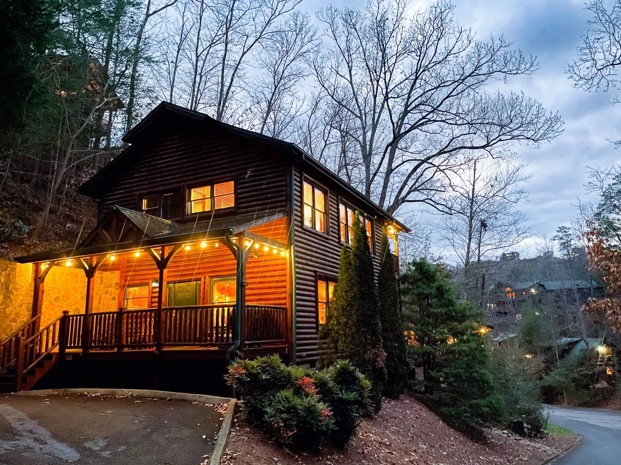 Rustic log cabin porch at dusk with glowing windows and string lights, a pancake breakfast spot nearby; Smoky Mountain