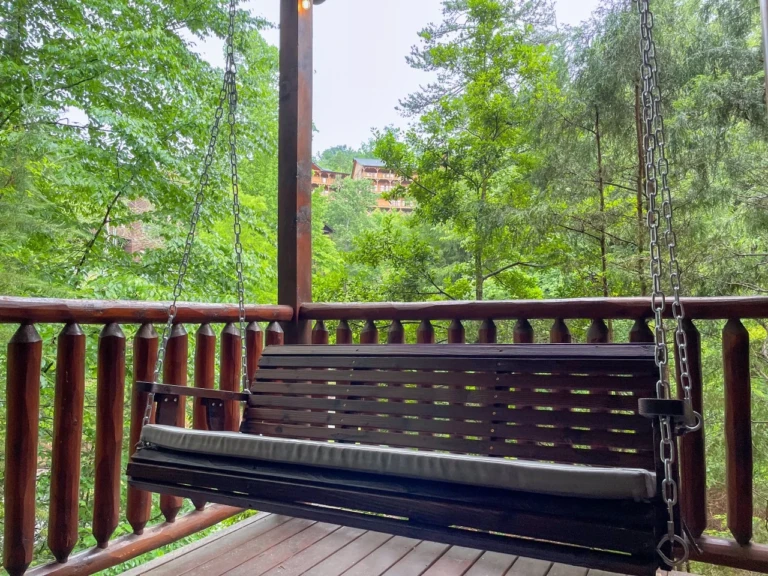 Rustic porch swing on wooden deck with mountain forest views at Gatlinburg cabin