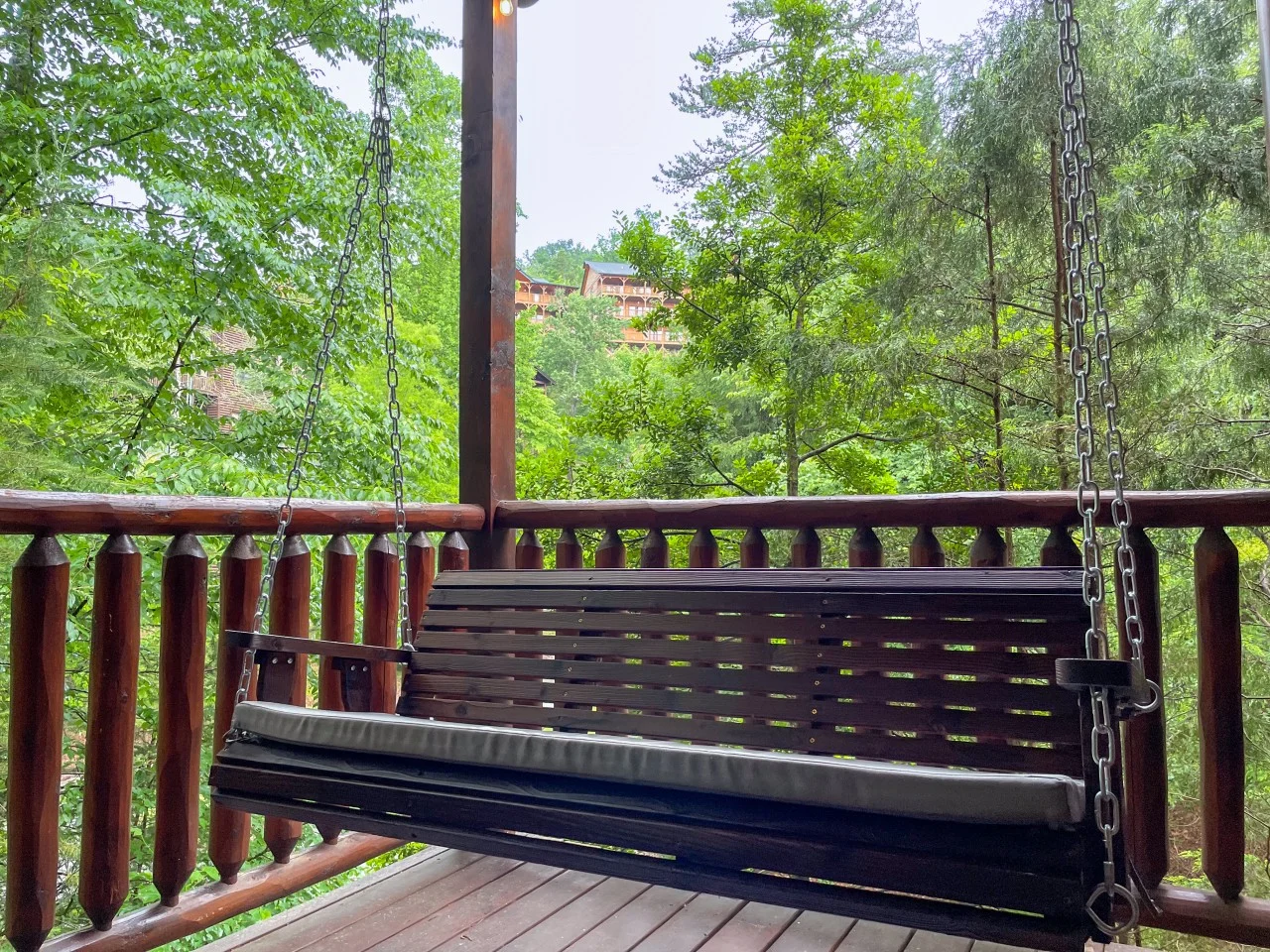 Porch swing on a cabin deck with green mountain backdrop for a first time visiting Gatlinburg