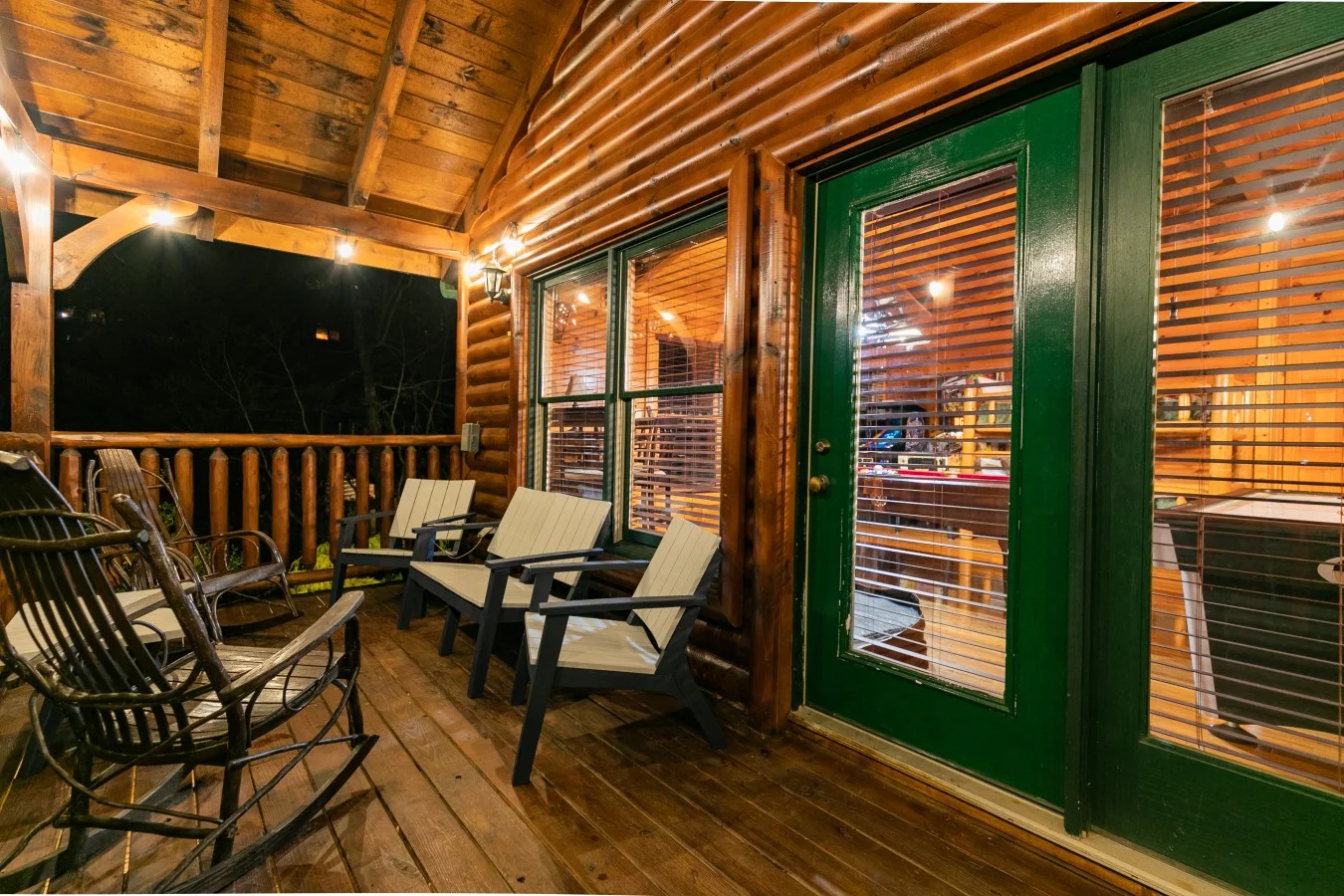 Rustic log cabin porch at night with Adirondack chairs and recliners, wood-beamed ceiling, and mountain views. Scenic drive