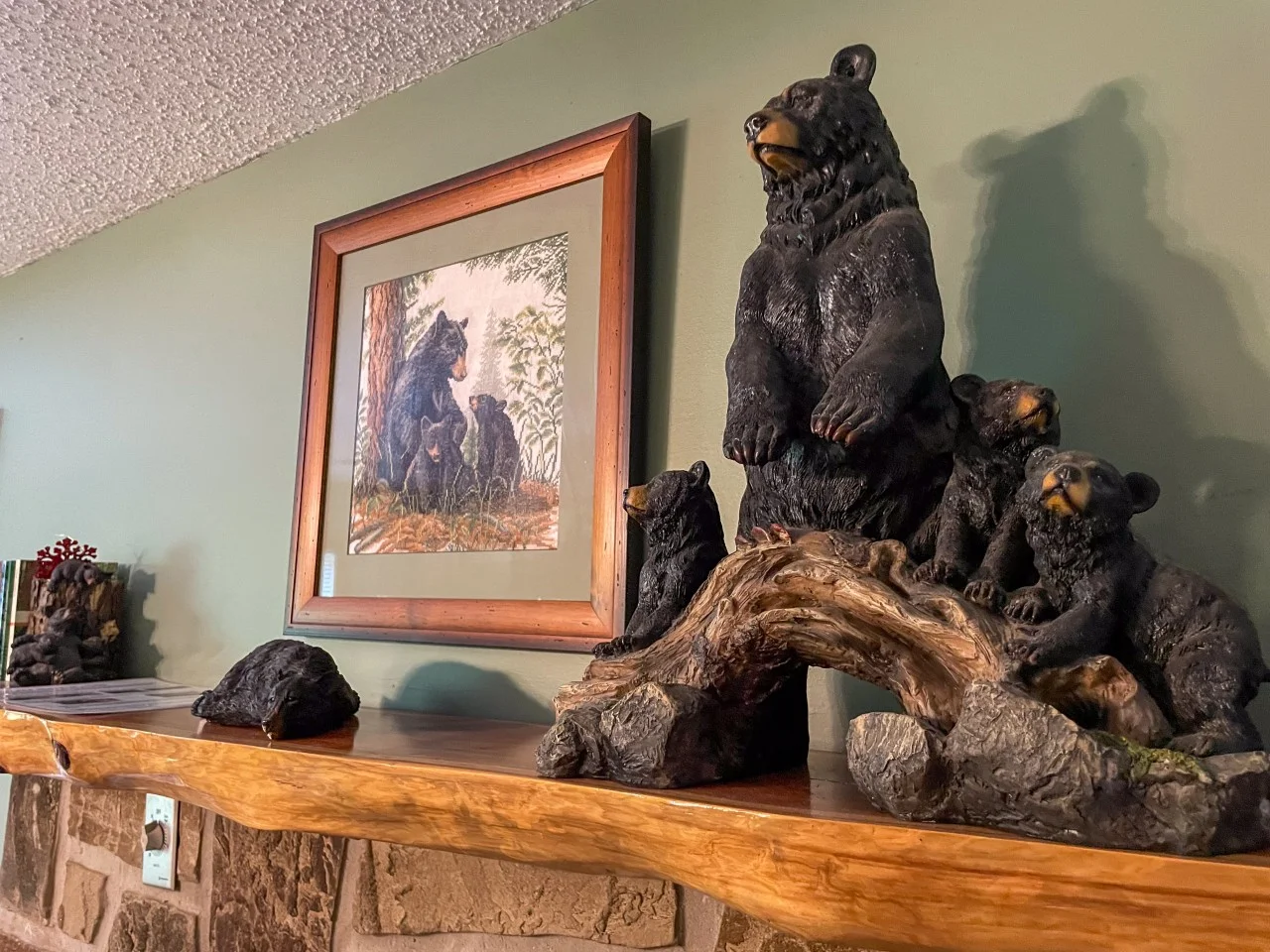 Bear-themed mountain cabin rental interior with black bear figurines and wildlife art on a rustic wooden shelf in