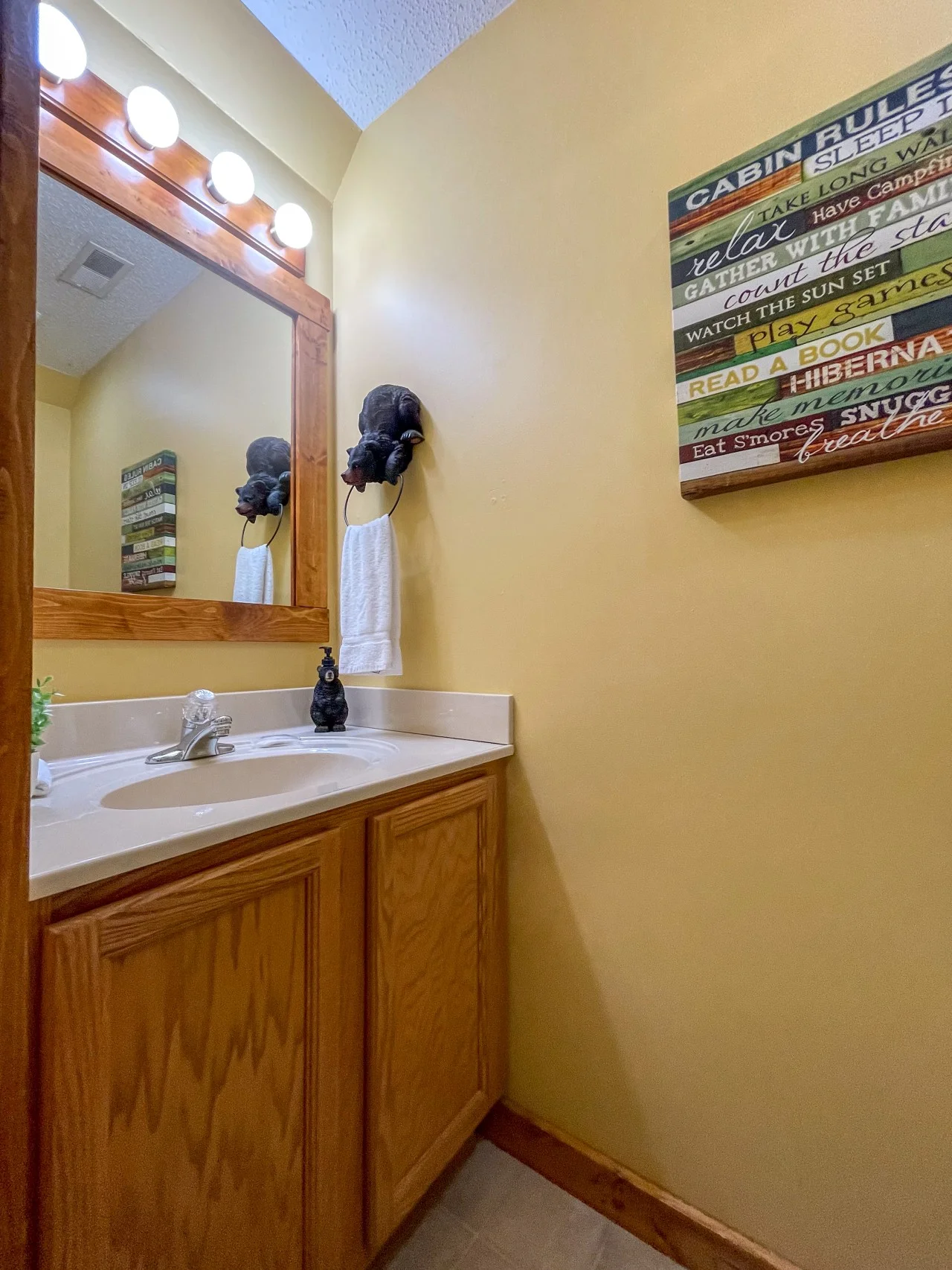 Cabin bathroom with wooden vanity, round sink, bear figurines and rustic mountain signs near Sevierville, TN at Bear Crest