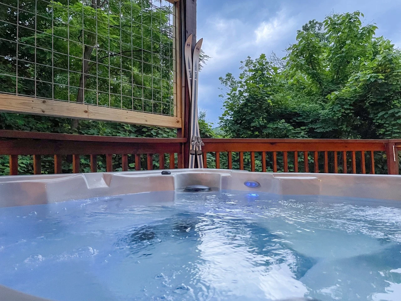 Steaming hot tub on a mountain deck with glass walls and wood railings overlooking forest, a cabin usa Pigeon Forge