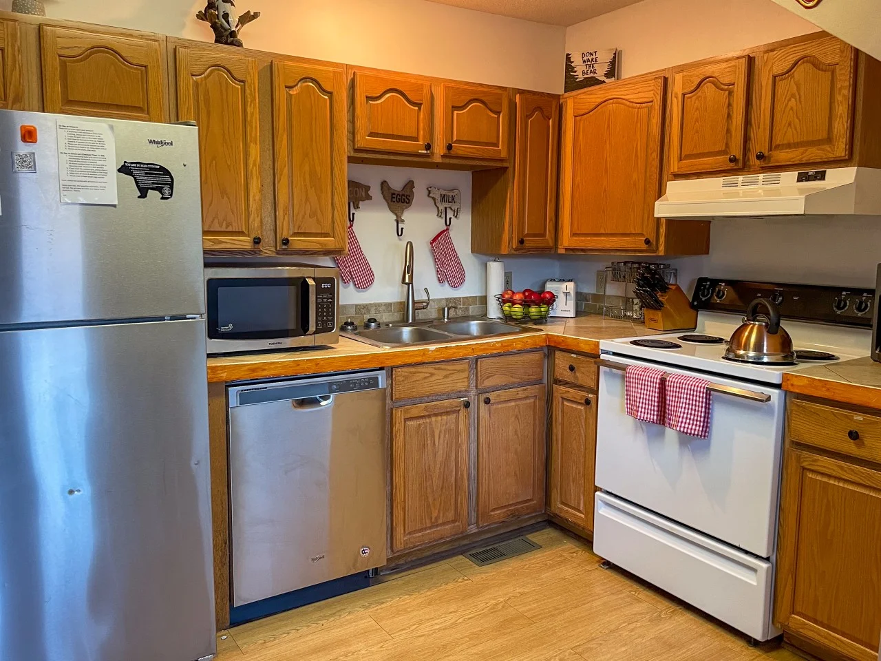 Rustic kitchen with warm wood cabinets, checkered red and white accents, and farm-themed wall hooks in a Gatlinburg, TN
